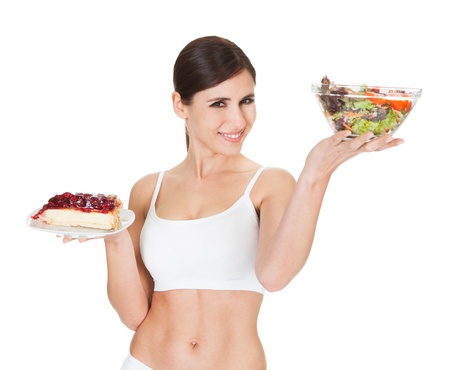 18882185 - young woman holding cake and salad on white background